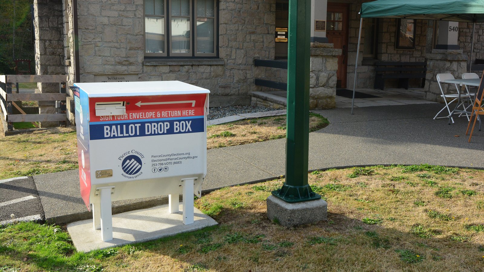 A white, red and blue Pierce County ballot drop box on the lawn outside the stone Town Hall in Wilkeson, Washington