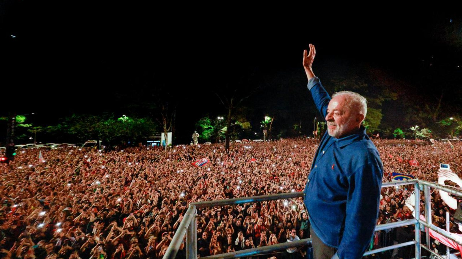 Luiz Inácio Lula da Silva raises his hand to a large nighttime crowd from a stage in São Paulo