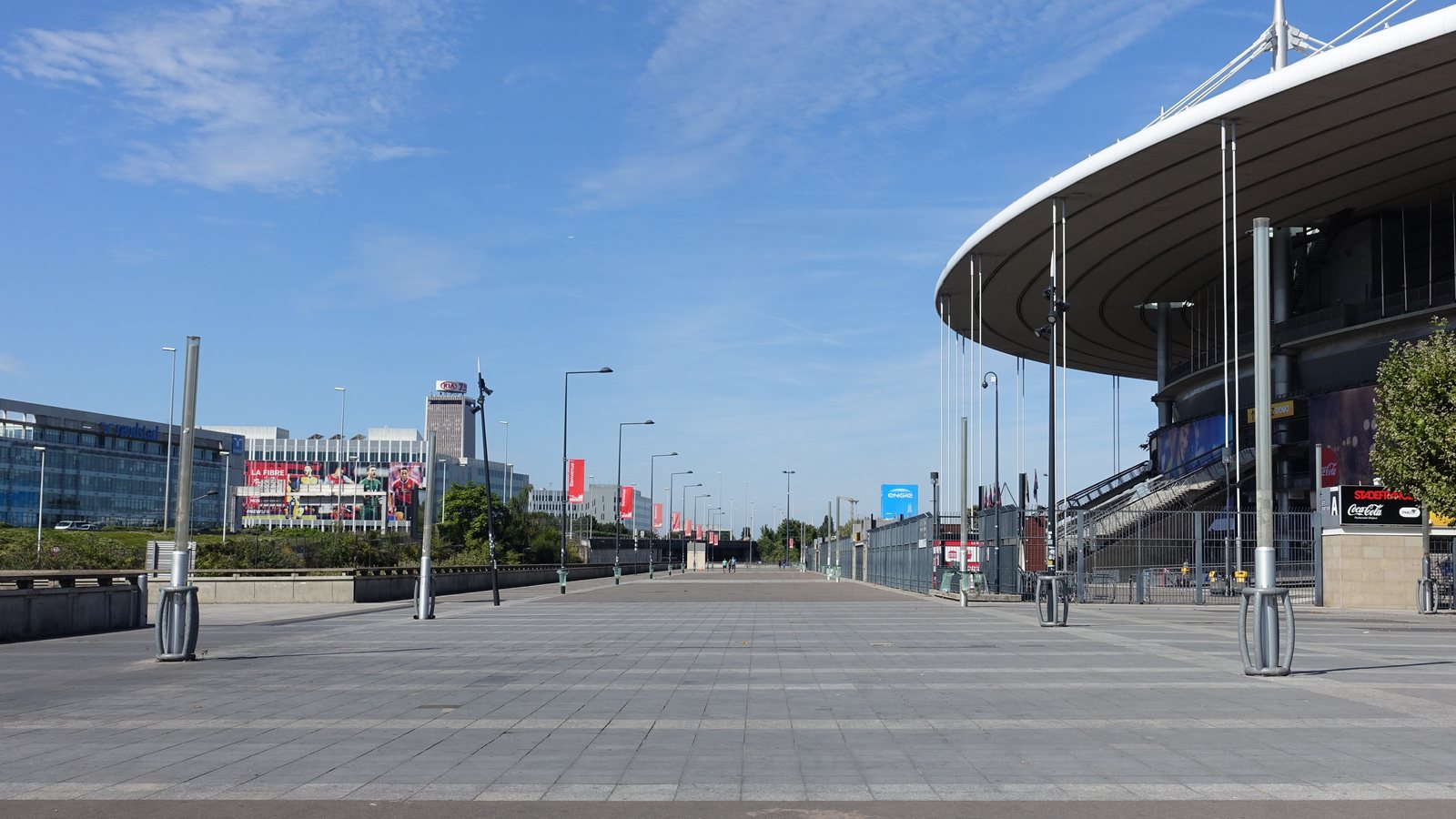 The curved roof and empty forecourt of Stade de France in Saint-Denis, north of Paris, on a sunny day