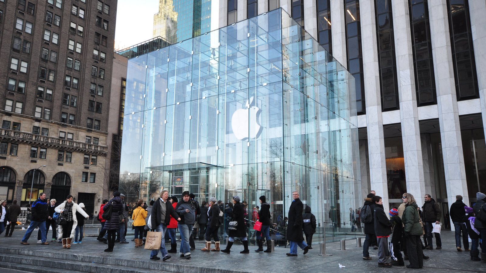 Shoppers walk past the glass cube entrance of Apple's Fifth Avenue store in New York