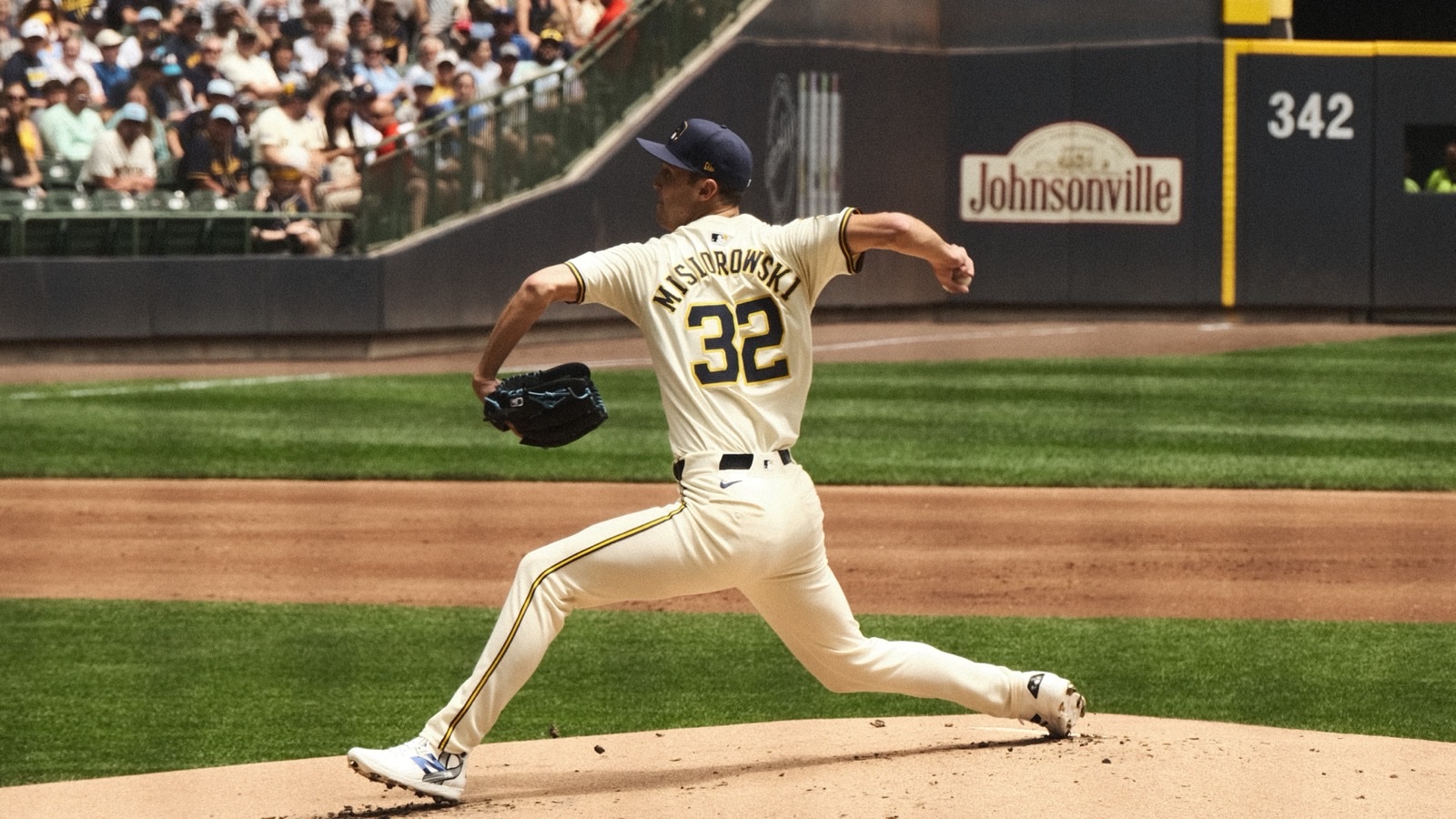 Brewers pitcher Jacob Misiorowski, number 32, in a cream home uniform, striding toward the plate mid-delivery on the mound at American Family Field