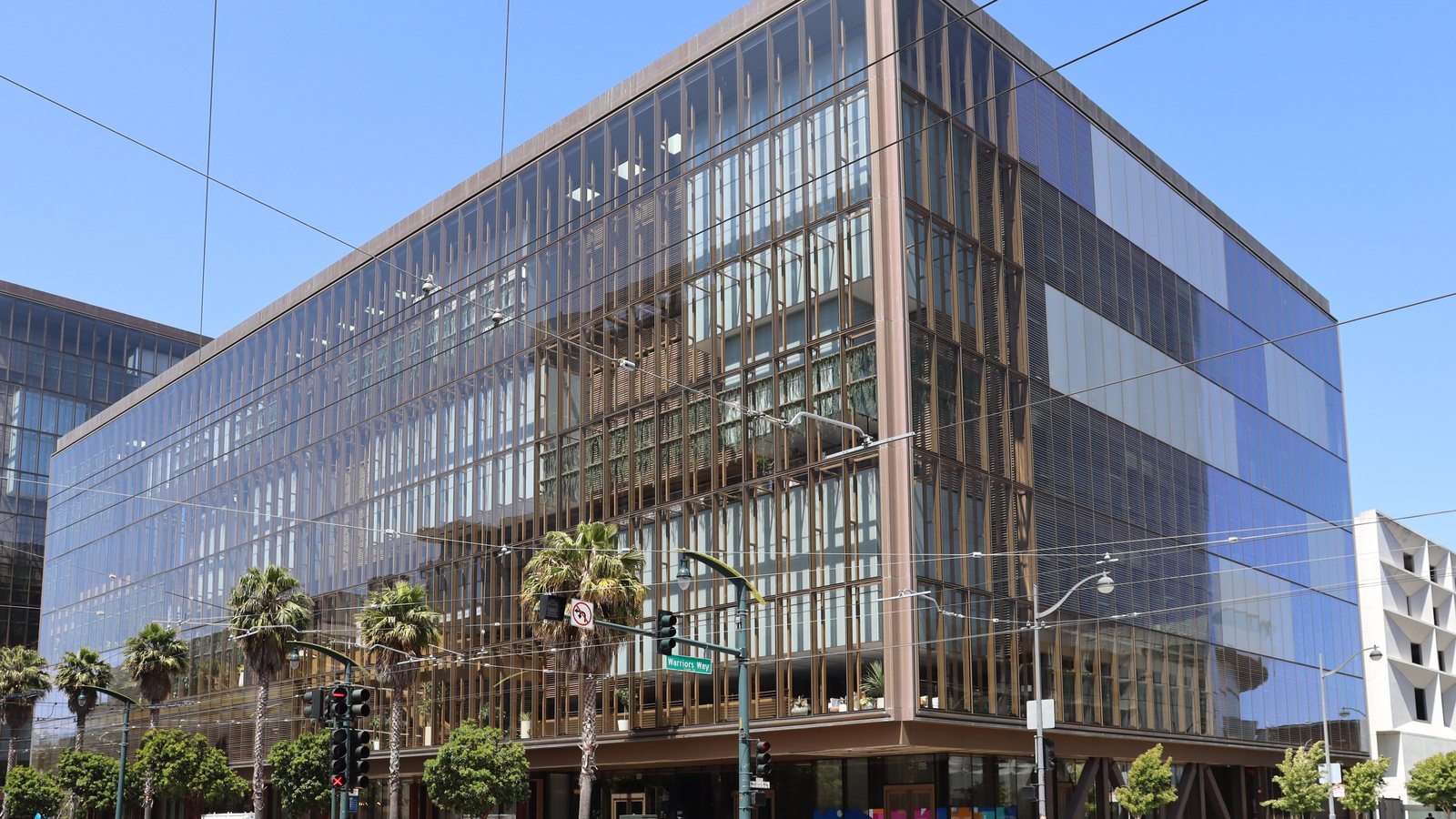 A glass-fronted office building lined with palm trees at 1515 Third Street in San Francisco's Mission Bay, under a blue sky