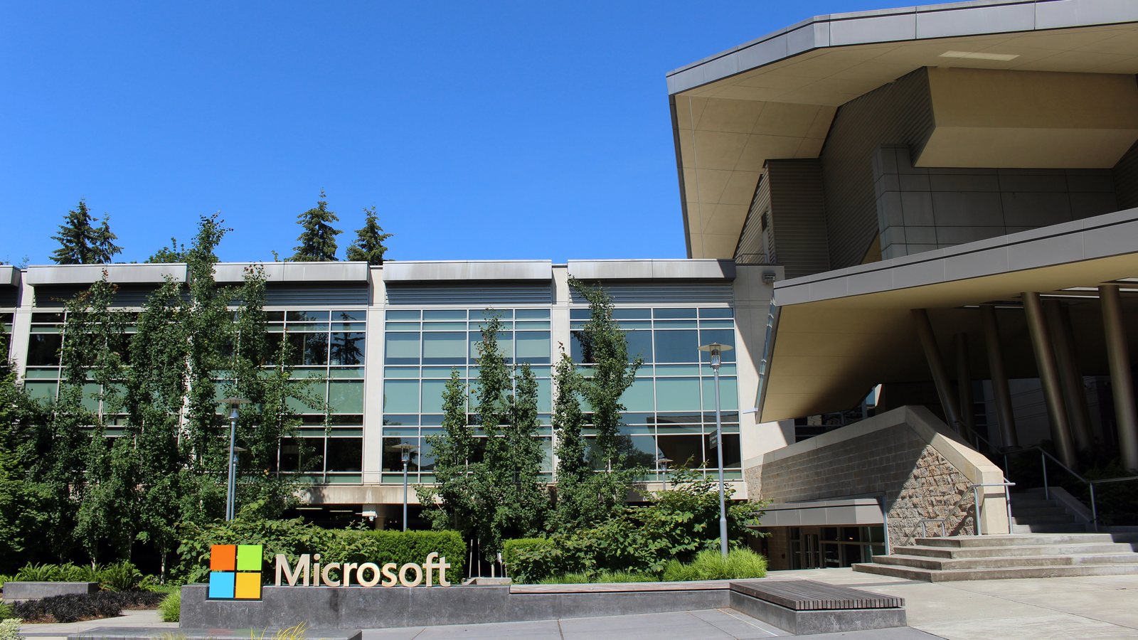 The Microsoft logo sign in front of Building 92 on the company's campus in Redmond, Washington, under a clear blue sky